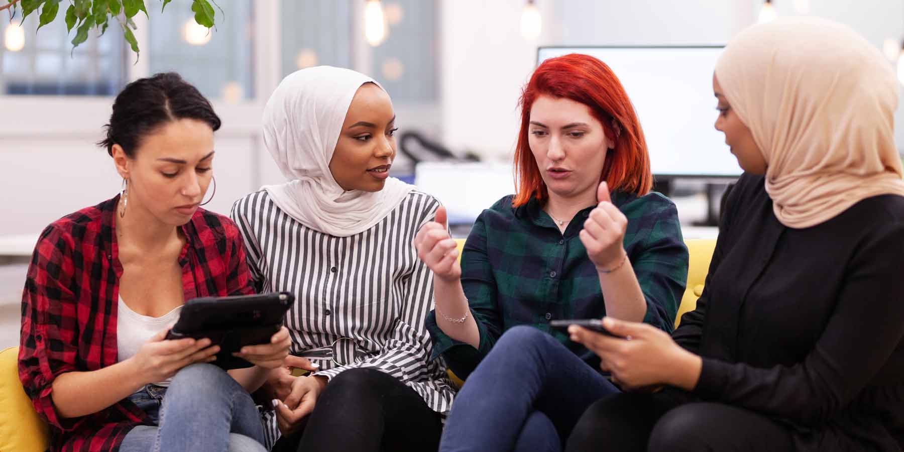 four women on a sofa discussing a topic